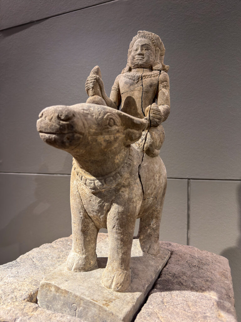 Escultura de una figura con tocado montada sobre un animal de cuatro patas.