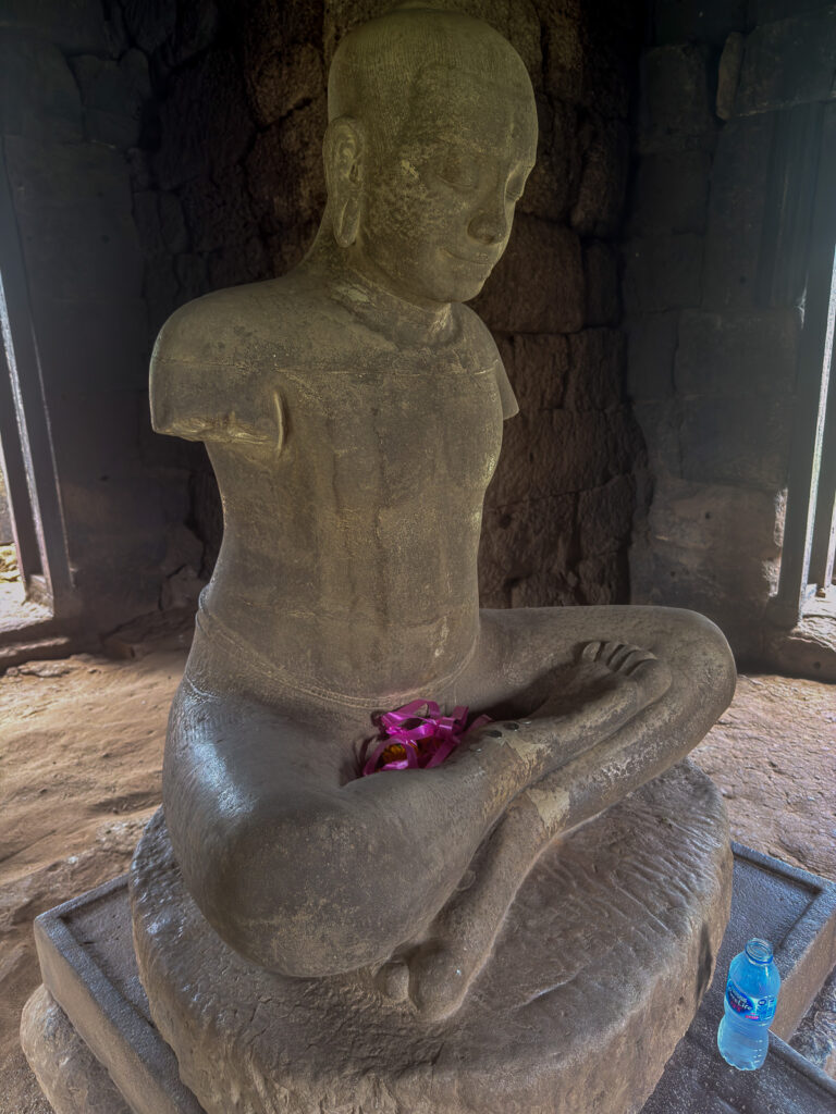 Escultura sentada con los brazos incompletos y flores en el regazo, en Phimai