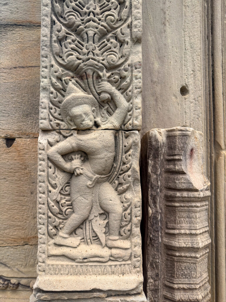 Figura tallada entre motivos vegetales en una jamba de piedra de Phimai